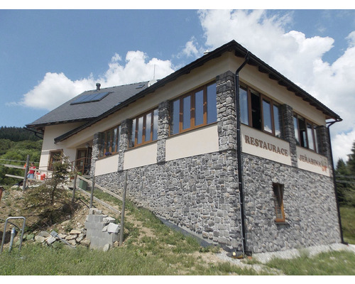 Vnější pohled na dvoupodlažní restauraci s kamennou fasádou a několika okny.
