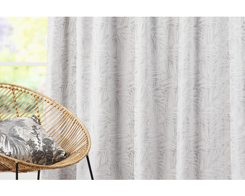 Dekorační látka s palmovým vzorem vedle proutěného křesla