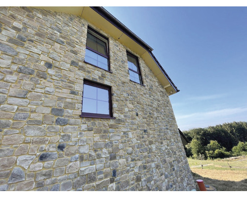 Fasáda domu s obkladem z přírodního kamene a okny