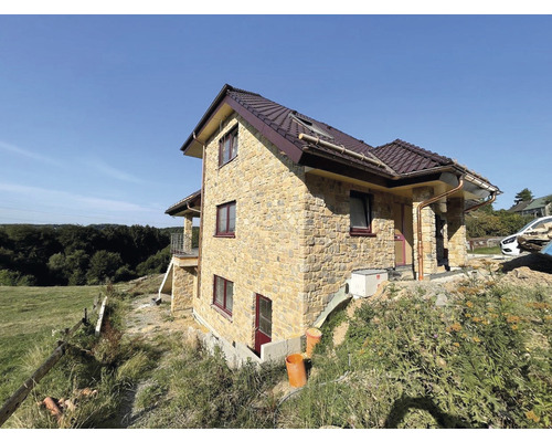 Dům s kamennou fasádou, hnědou střechou a okapy