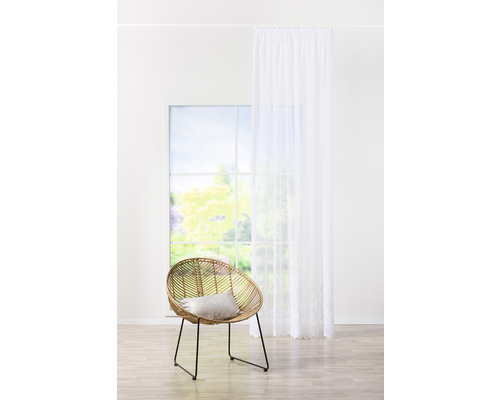 Světlá místnost s ratanovým křeslem, polštářem, oknem a závěsem