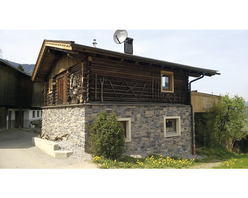 Dřevěný dům s kamennými základy a satelitní anténou