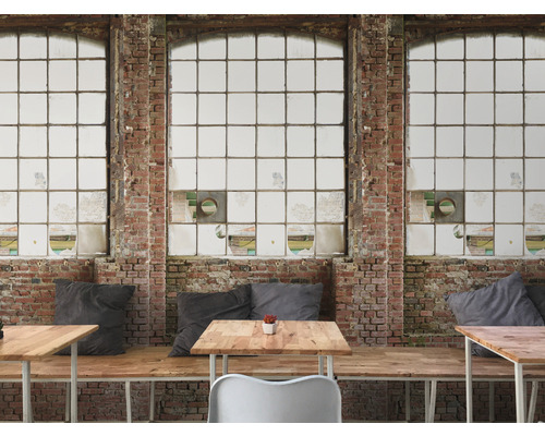 Interiér s cihlovou stěnou a velkými okny a také stoly a posezení.