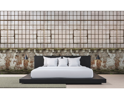 Ložnice s postelí před cihlovou zdí a velkými okny