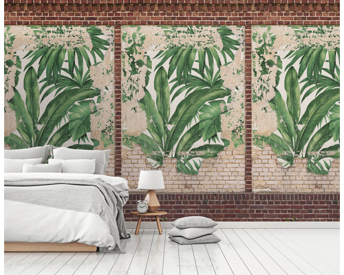 Nástěnná dekorace s motivem tropických listů v místnosti s postelí a cihlovou zdí