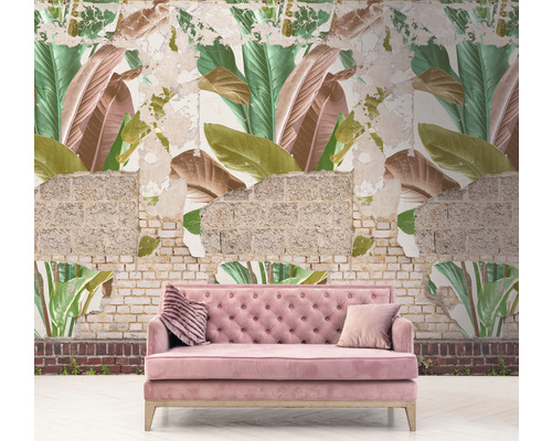Růžová pohovka před zdí s tapetou s motivem listů a odhaleným zdivem