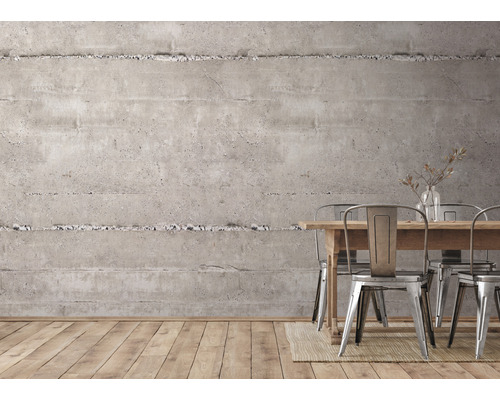 Interiér s betonovou stěnou, dřevěným stolem a kovovými židlemi.