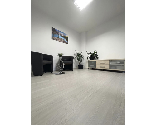 Světlá místnost s laminátovou podlahou, křesly a televizním nábytkem