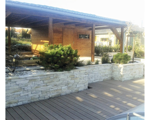 Exteriér s dřevěným zahradním domkem, zdí z přírodního kamene a dřevěnou terasou