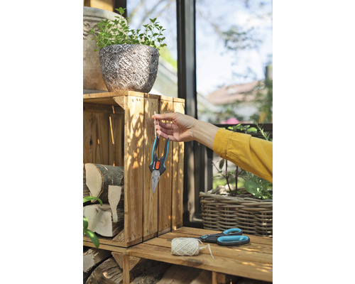 Scéna ze zahrady s truhlíkem, poleny, zahradními nůžkami a osobou