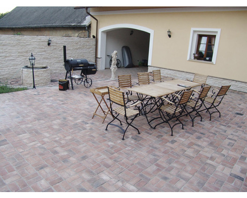 Venkovní prostor s grilem, stolem a židlemi na dlažebních kostkách
