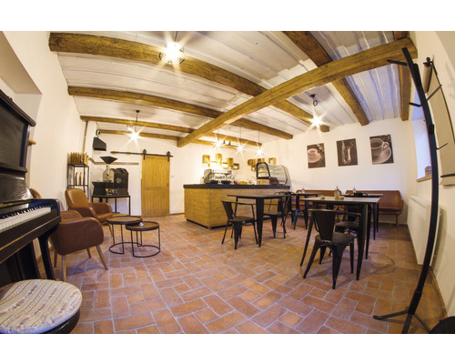 Interiér kavárny se stoly, židlemi, barem, kávovarem a dekoracemi