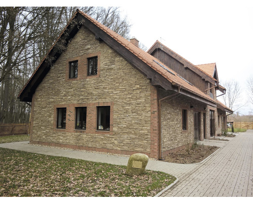 Pohled na budovu s fasádou z kamenných obkladových pásků a taškovou střechou