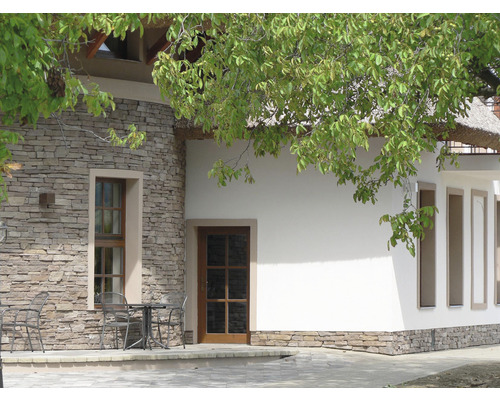 Exteriér budovy s kamennou zdí, okny a dveřmi