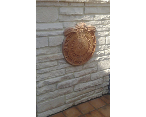 Dekorativní nástěnné hodiny s římskými číslicemi a znameními zvěrokruhu na kamenné zdi