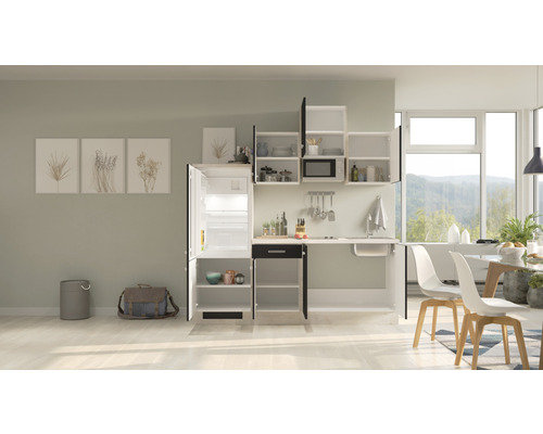 Kompaktní kuchyňská linka s dřezem, lednicí, závěsnými skříňkami a jídelním stolem ve světlém pokoji