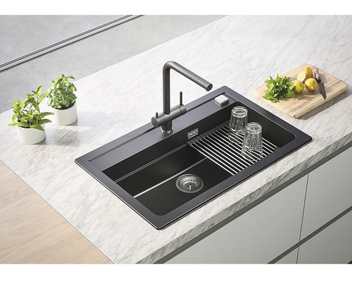 Černý kuchyňský dřez s odkapávačem, baterií a příslušenstvím na kuchyňské lince.