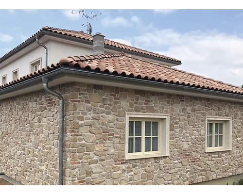 Fasáda domu s obkladem z přírodního kamene a okapem