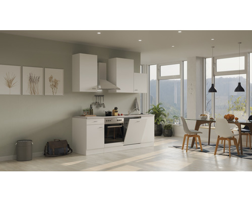 Moderní kuchyně s bílými skříňkami, odsavačem par a jídelním koutem ve světlé místnosti.