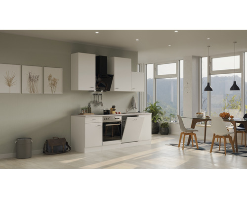 Světlá vestavěná kuchyně s bílými skříňkami, odsavačem par a jídelním prostorem se stolem a židlemi.