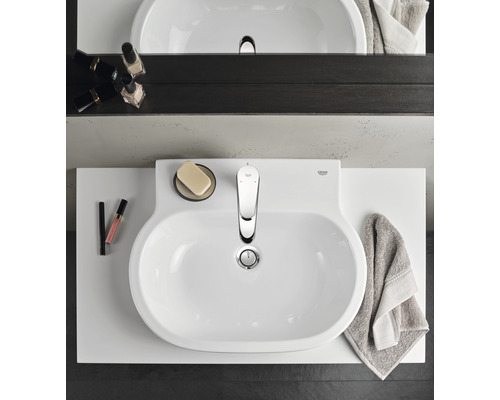 Pohled shora na koupelnu s umyvadlem, baterií a koupelnovými doplňky.