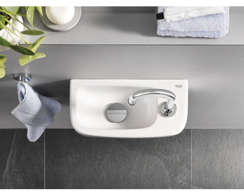 Fotografie koupelny s umyvadlem na desku a logem Grohe.