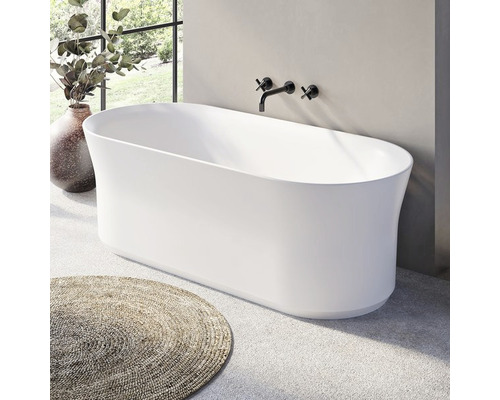 Volně stojící vana v koupelně s armaturami a kulatým kobercem