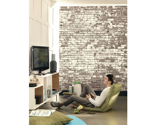 Obývací pokoj s cihlovou zdí, televizí a mužem hrajícím videohru