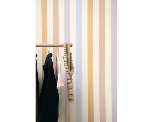 Pohled na pokoj s pruhovanou tapetou a věšákem na oblečení.