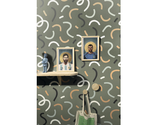 Dekorativní pokoj se vzorovanou tapetou, policí, obrazy a věšáky.