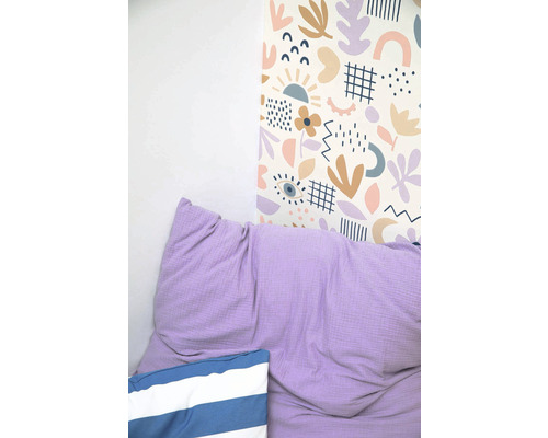 Stěna s tapetou s abstraktním vzorem, fialový polštář a pruhovaný polštář