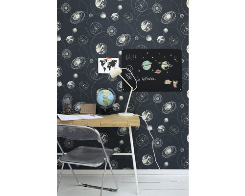 Pokoj se stolem, židlí, lampou a tapetou s astronomickými motivy