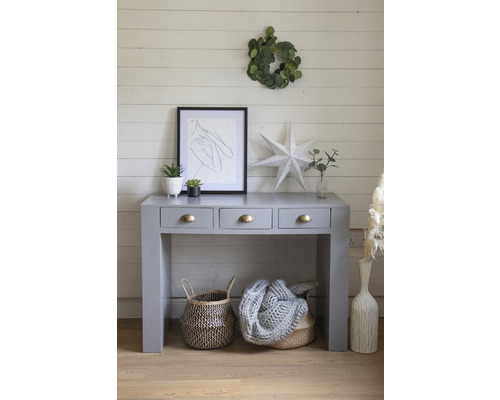 Šedý konzolový stolek se třemi zásuvkami, košíky a dekoracemi na dřevěné podlaze