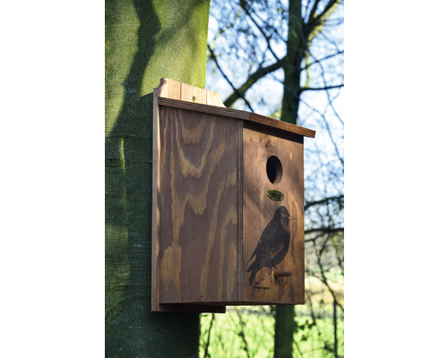 Dřevěná ptačí budka s motivem ptáka připevněná ke stromu