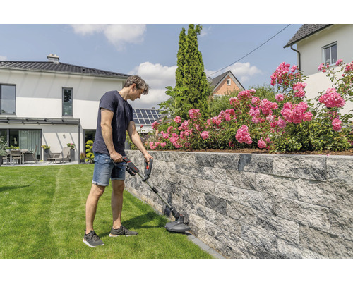 Muž používá vyžínač v zahradě.