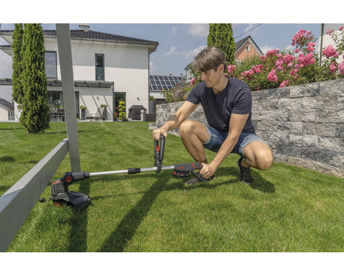 Muž montuje akumulátorový vyžínač na trávu na zahradě.