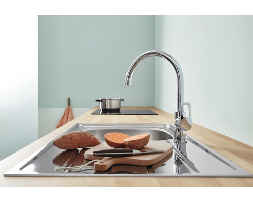 Kuchyňský dřez s baterií, prkénkem a sladkými bramborami na pracovní desce