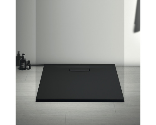 Černá sprchová vanička s odtokovou soupravou v koupelně.