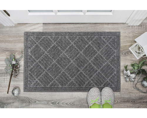 Šedá rohožka s geometrickým vzorem před dveřmi
