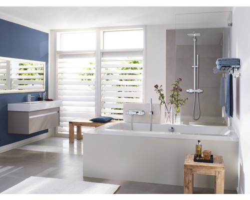 Koupelna s vanou, umyvadlem, zrcadlem a okny se žaluziemi pro světlé prostředí.