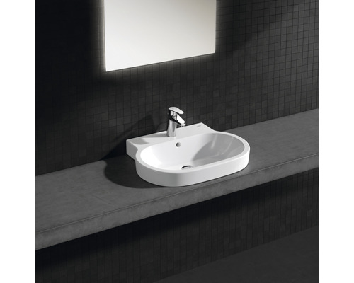 Umyvadlo s baterií na polici před tmavou stěnou se zrcadlem