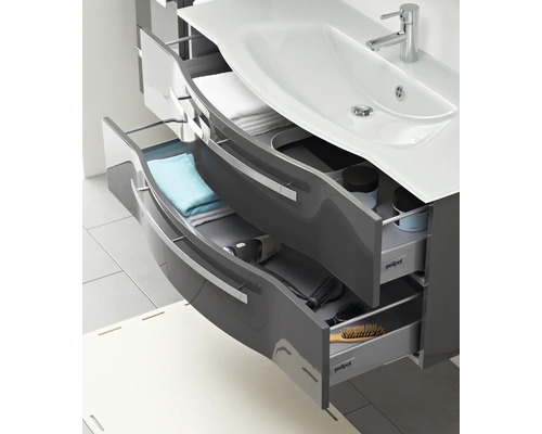 Skříňka pod umyvadlo s otevřenými zásuvkami a různými koupelnovými doplňky