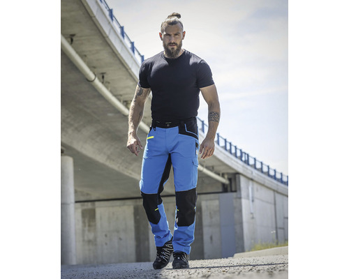 Muž venku nosí modré a černé pracovní kalhoty