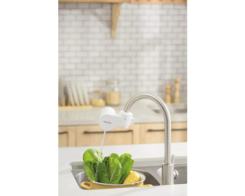 Kuchyňská scéna s namontovaným kohoutkovým filtrem značky Philips při mytí zeleniny
