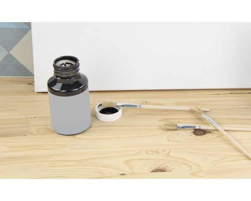 Kbelík s barvou a štětci na dřevěném pozadí