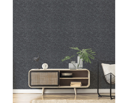 Detailní záběr na texturovanou tmavou tapetu v obývacím pokoji, kombinovaný s dřevěnou skříňkou a kovovou židlí.