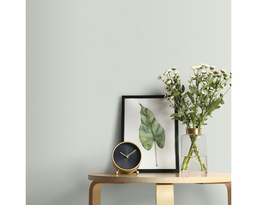 Obývací pokoj s stolem, hodinami, květinami a zarámovaným obrazem na zdi