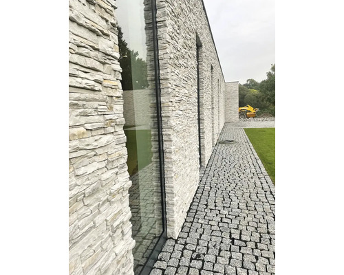Exteriér moderní budovy s fasádou z přírodního kamene a dlážděnou cestou