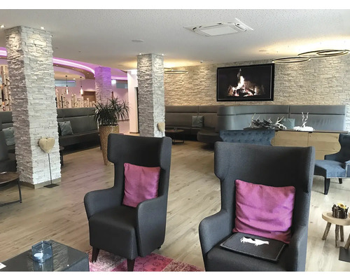 Vstupní hala hotelu s křesly, pohovkami a dekorativním kamenným sloupem