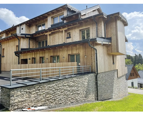 Vícepodlažní budova s dřevěnou fasádou a kamennou zdí